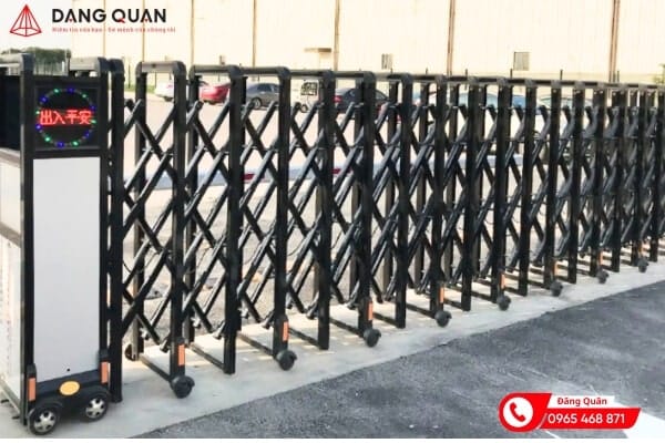 Cổng xếp tự động DQ17 thân nhôm màu đen, lưới chéo dày, đầu kéo có màn hình LED chữ đỏ, lắp trên nền bê tông