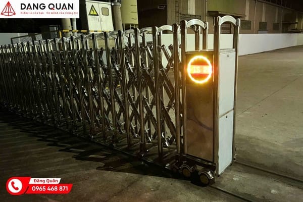 Cổng xếp inox tự động trước nhà xưởng lúc trời tối, đầu kéo có đèn LED tròn báo hiệu