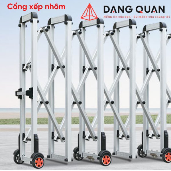Cổng xếp nhôm kéo tay màu bạc, trụ đứng đầu bo tròn có dải phản quang, lưới chéo chữ X, bánh xe ở chân trụ