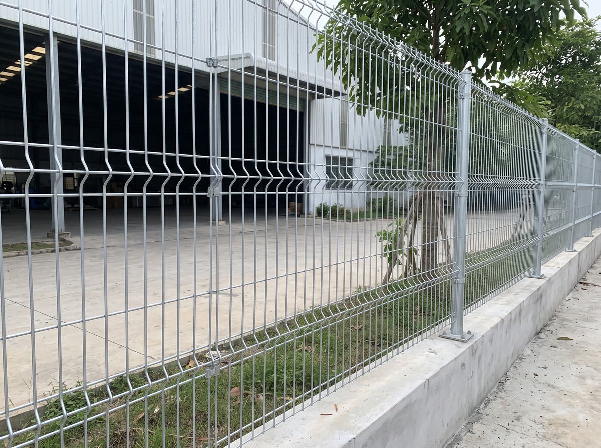 Hàng rào lưới thép hàn dạng tấm chấn sóng mạ kẽm quanh nhà xưởng, trụ tròn bắt bản mã trên tường bê tông