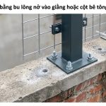 Trụ thép hộp hàng rào bắt bản mã bằng bốn bu lông lên đầu tường gạch cũ, cạnh đó là lỗ khoan cấy thanh ren bằng keo hóa chất